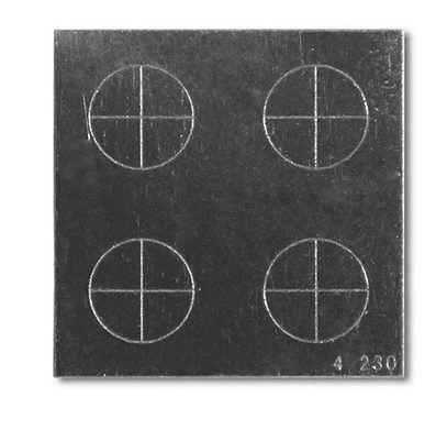 Magnaflux QQI Model CX4-230, featuring four circle-cross notch patterns on a steel shim, designed for demonstrating magnetic field strength and direction.